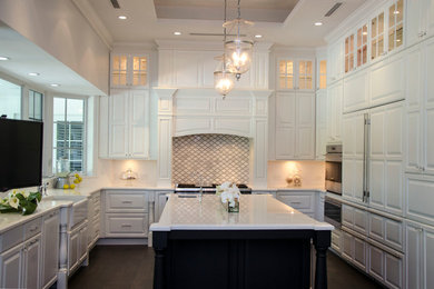 Inspiration for a large transitional u-shaped enclosed kitchen remodel in Miami with a farmhouse sink, raised-panel cabinets, white cabinets, quartz countertops, gray backsplash, porcelain backsplash, paneled appliances and an island
