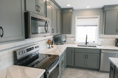 Klassisk inredning av ett vit vitt l-kök, med skåp i shakerstil, grå skåp, bänkskiva i kvarts, rostfria vitvaror och en köksö