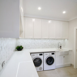 Immagine di una grande lavanderia multiuso con lavello stile country, ante con riquadro incassato, ante bianche, top in quarzo composito, paraspruzzi grigio, paraspruzzi in marmo, pareti grigie, pavimento con piastrelle in ceramica, lavatrice e asciugatrice affiancate, pavimento grigio e top bianco