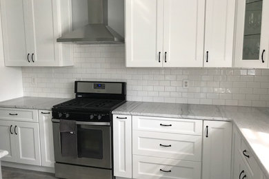 Inspiration for a large country l-shaped open plan kitchen in Philadelphia with an undermount sink, shaker cabinets, white cabinets, quartzite benchtops, white splashback, subway tile splashback, stainless steel appliances, vinyl floors, with island and grey floor.