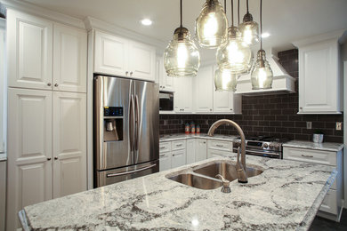 Kitchen - mid-sized transitional l-shaped kitchen idea in Other with a double-bowl sink, raised-panel cabinets, white cabinets, quartz countertops, gray backsplash, subway tile backsplash, stainless steel appliances and an island