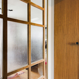 Aménagement d'un petit hall d'entrée éclectique avec un mur vert, une porte coulissante et une porte en bois clair.