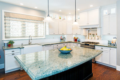 Inspiration for a mid-sized timeless l-shaped medium tone wood floor and brown floor kitchen remodel in Other with a farmhouse sink, recessed-panel cabinets, white cabinets, granite countertops, gray backsplash, subway tile backsplash, stainless steel appliances and an island