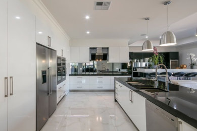 This is an example of a mid-sized contemporary l-shaped kitchen in Adelaide with a double-bowl sink, flat-panel cabinets, white cabinets, quartz benchtops, metallic splashback, mirror splashback, stainless steel appliances, porcelain floors and a peninsula.
