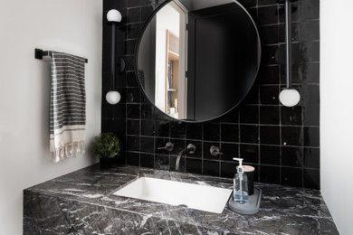 ニューヨークにあるモダンスタイルのおしゃれな浴室 (黒いタイル、セラミックタイル、黒い洗面カウンター、洗面台1つ、フローティング洗面台) の写真