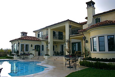 Example of a large tuscan yellow three-story stucco exterior home design in Los Angeles