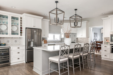 Inspiration for a mid-sized country l-shaped dark wood floor and brown floor eat-in kitchen remodel in Charlotte with an undermount sink, shaker cabinets, white cabinets, quartz countertops, gray backsplash, subway tile backsplash, stainless steel appliances, an island and white countertops