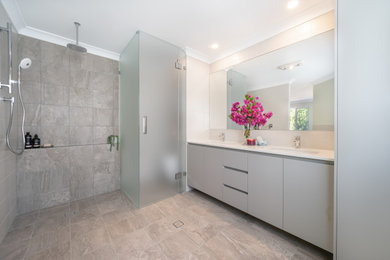 This is an example of a large contemporary master bathroom in Perth with flat-panel cabinets, grey cabinets, an open shower, a one-piece toilet, beige tile, gray tile, porcelain tile, beige walls, porcelain floors, a drop-in sink, engineered quartz benchtops, beige floor, an open shower, white benchtops, an enclosed toilet, a niche, a double vanity and a floating vanity.