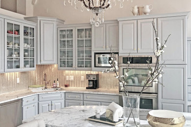Large traditional l-shaped open plan kitchen in Denver with grey cabinets, marble benchtops, metallic splashback, glass tile splashback, light hardwood floors, with island, white benchtop and vaulted.
