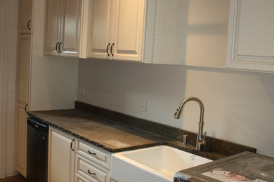 Utility room - mid-sized traditional medium tone wood floor utility room idea in New York with a farmhouse sink, raised-panel cabinets, white cabinets, granite countertops, white walls and a side-by-side washer/dryer