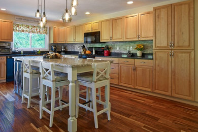 Eat-in kitchen - mid-sized traditional l-shaped medium tone wood floor eat-in kitchen idea in Providence with raised-panel cabinets, light wood cabinets, granite countertops, beige backsplash, stone tile backsplash, black appliances and an island