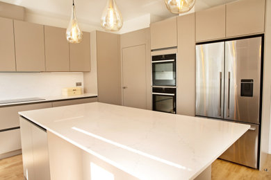 Design ideas for a large contemporary grey and white l-shaped open plan kitchen in London with a built-in sink, flat-panel cabinets, grey cabinets, quartz worktops, white splashback, stone slab splashback, stainless steel appliances, medium hardwood flooring, multiple islands, beige floors, white worktops and feature lighting.