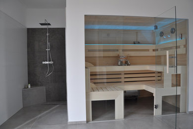 Kleine Nordische Sauna mit bodengleicher Dusche, grauem Boden und offener Dusche in München
