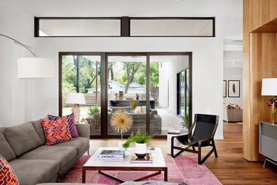 Midcentury open concept living room in Austin with white walls and medium hardwood floors.