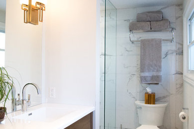 Example of a mid-sized trendy 3/4 white tile and stone tile marble floor corner shower design in Toronto with flat-panel cabinets, dark wood cabinets, a one-piece toilet, white walls, an integrated sink and quartz countertops