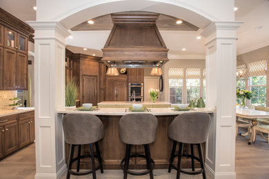 Eat-in kitchen - large transitional l-shaped medium tone wood floor and beige floor eat-in kitchen idea in San Francisco with an undermount sink, recessed-panel cabinets, quartzite countertops, glass tile backsplash, paneled appliances, two islands, dark wood cabinets and beige countertops