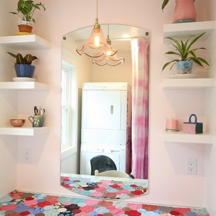 ロサンゼルスの中サイズのコンテンポラリースタイルのおしゃれな洗濯室 (フラットパネル扉のキャビネット、白いキャビネット、ガラスカウンター、ベージュの壁、セラミックタイルの床、上下配置の洗濯機・乾燥機、青い床) の写真