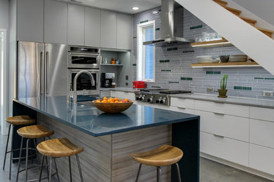 Photo of a mid-sized contemporary l-shaped kitchen in Raleigh with an undermount sink, flat-panel cabinets, white cabinets, quartz benchtops, multi-coloured splashback, matchstick tile splashback, stainless steel appliances, concrete floors, with island, grey floor and grey benchtop.