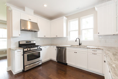 Traditional kitchen in Atlanta with an undermount sink, shaker cabinets, white cabinets, granite benchtops, white splashback, subway tile splashback, stainless steel appliances, a peninsula and brown floor.