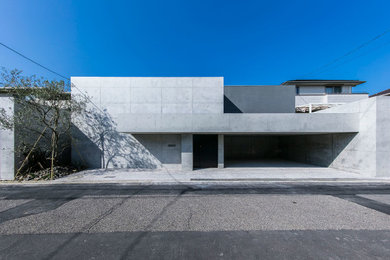 Cette photo montre une grande façade de maison grise moderne à un étage avec un toit plat.