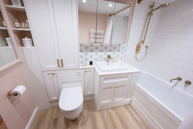 Inspiration for a small classic family bathroom in Kent with shaker cabinets, white cabinets, a built-in bath, a shower/bath combination, a one-piece toilet, white tiles, porcelain tiles, pink walls, solid surface worktops, a shower curtain, white worktops, feature lighting, a single sink and a built in vanity unit.