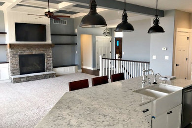 Example of a mid-sized transitional l-shaped dark wood floor and brown floor open concept kitchen design in Other with a farmhouse sink, shaker cabinets, white cabinets, quartzite countertops, white backsplash, subway tile backsplash, stainless steel appliances and an island