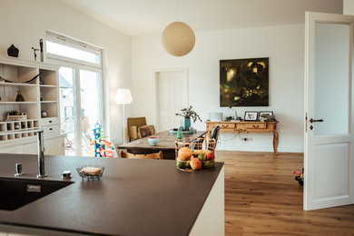 Geschlossenes, Mittelgroßes Landhaus Esszimmer ohne Kamin mit weißer Wandfarbe, braunem Holzboden und braunem Boden in Köln