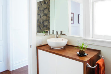 Inspiration for a mid-sized 1950s 3/4 white tile and ceramic tile ceramic tile bathroom remodel in San Francisco with a vessel sink, furniture-like cabinets, white cabinets, wood countertops and white walls