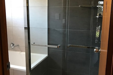 This is an example of a small contemporary master bathroom in Melbourne with white cabinets, a drop-in tub, a corner shower, black and white tile, ceramic tile, white walls, ceramic floors, an undermount sink and engineered quartz benchtops.