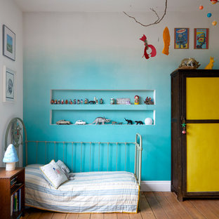 Design ideas for an eclectic gender neutral toddler’s room in London with blue walls, medium hardwood flooring and brown floors.
