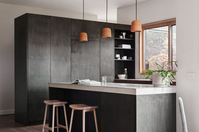 Photo of a contemporary kitchen in Melbourne with flat-panel cabinets, dark wood cabinets, medium hardwood floors and white benchtop.