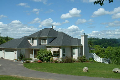 This is an example of a large two-storey beige exterior in Bridgeport with wood siding and a clipped gable roof.