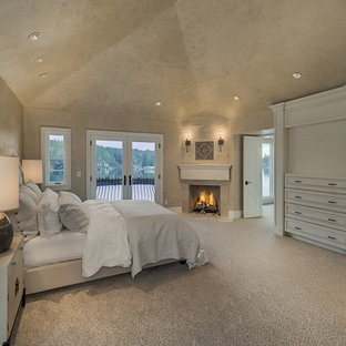 Неиссякаемый источник вдохновения для домашнего уюта: огромная хозяйская спальня в средиземноморском стиле с бежевыми стенами, ковровым покрытием, угловым камином, фасадом камина из камня и бежевым полом