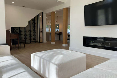 Example of a large trendy open concept vinyl floor and beige floor living room design in Tampa with a bar, white walls, a standard fireplace and a wall-mounted tv
