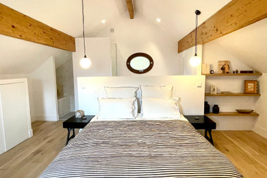 Cette image montre une chambre parentale blanche et bois traditionnelle de taille moyenne avec un mur blanc, parquet clair et un sol beige.