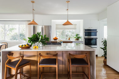 Example of a mid-century modern u-shaped light wood floor and brown floor open concept kitchen design in DC Metro with flat-panel cabinets, medium tone wood cabinets, quartzite countertops, white backsplash, subway tile backsplash, an island and gray countertops