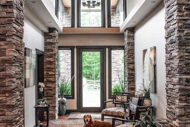 Arts and crafts medium tone wood floor and brown floor entryway photo in New York with gray walls and a glass front door
