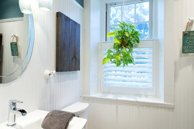 Mid-sized beach style bathroom in Toronto with multi-coloured walls, porcelain floors, a pedestal sink, glass benchtops, a two-piece toilet and a corner shower.