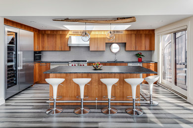 Inspiration for a large coastal l-shaped gray floor kitchen remodel in Boston with an undermount sink, flat-panel cabinets, medium tone wood cabinets, gray backsplash, stainless steel appliances and an island
