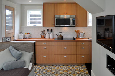 Small trendy single-wall cement tile floor and yellow floor eat-in kitchen photo in Portland with a drop-in sink, flat-panel cabinets, wood countertops, white backsplash, ceramic backsplash, stainless steel appliances and no island