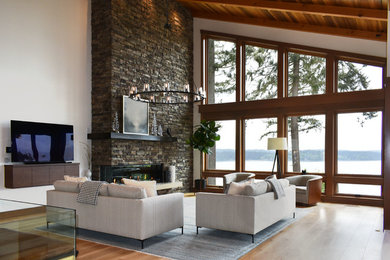 Inspiration for a country open concept living room in Seattle with white walls, light hardwood floors, a ribbon fireplace, a stone fireplace surround and beige floor.