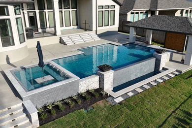 Inspiration for a large modern backyard rectangular infinity pool house remodel in Houston with decking