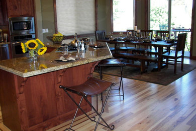 Inspiration for a large rustic l-shaped medium tone wood floor open concept kitchen remodel in Other with a drop-in sink, shaker cabinets, medium tone wood cabinets, granite countertops, green backsplash, ceramic backsplash, stainless steel appliances and an island