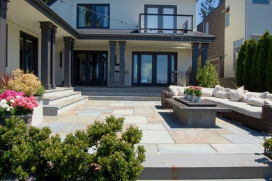 Example of a mid-sized arts and crafts backyard stone patio design in Other with a fire pit and a roof extension