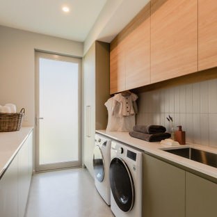 Foto di una grande lavanderia multiuso minimal con lavello integrato, ante in legno chiaro, top in laminato, paraspruzzi grigio, paraspruzzi con piastrelle diamantate, lavatrice e asciugatrice affiancate, pavimento bianco e top bianco