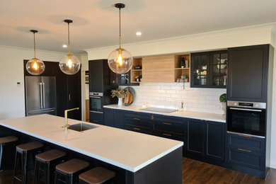 Photo of a large contemporary single-wall kitchen in Other with recessed-panel cabinets, white splashback, ceramic splashback, an island and brown floors.