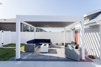Modelo de patio moderno de tamaño medio en patio trasero con adoquines de hormigón y pérgola