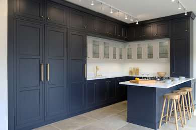This is an example of a medium sized contemporary u-shaped kitchen/diner in Berkshire with a single-bowl sink, beaded cabinets, blue cabinets, quartz worktops, white splashback, engineered quartz splashback, integrated appliances, porcelain flooring, a breakfast bar, beige floors, white worktops and feature lighting.