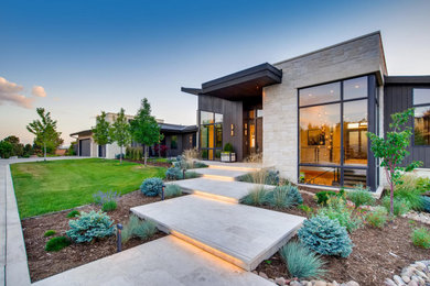 Mid-sized trendy two-story stone house exterior photo in Denver with a black roof