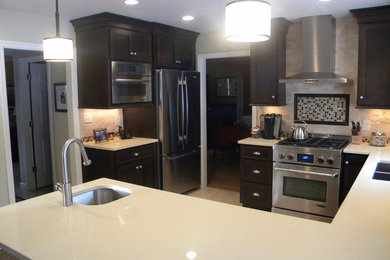 Example of a mid-sized trendy u-shaped travertine floor and beige floor eat-in kitchen design in Other with an undermount sink, recessed-panel cabinets, black cabinets, quartz countertops, stainless steel appliances, no island, beige backsplash and stone tile backsplash